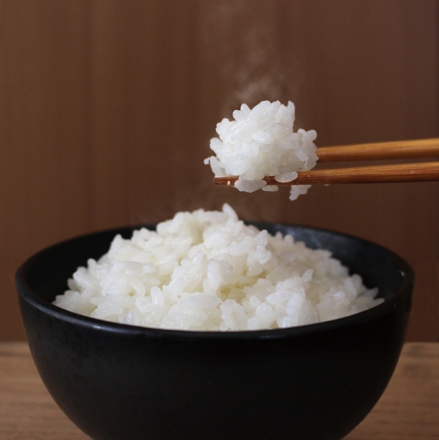 お茶碗から箸でご飯を持ち上げているところ