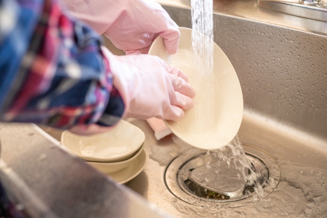 ゴム手袋をして食器洗いをしている手元