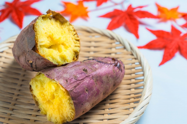 紅葉したモミジの葉っぱとザルにのった焼き芋